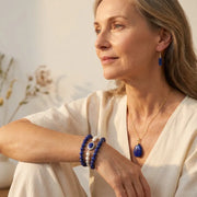 Woman wearing gold lapis lazuli drop earrings — throat chakra jewelry for truth and calm