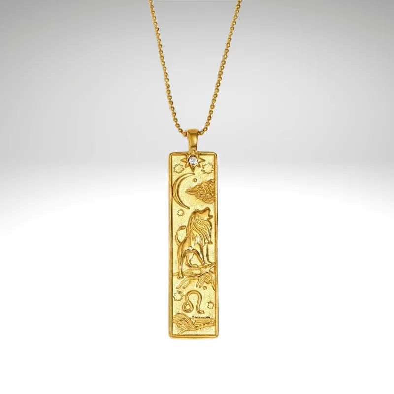 Gold pendant with zodiac design on a chain against a light gray background