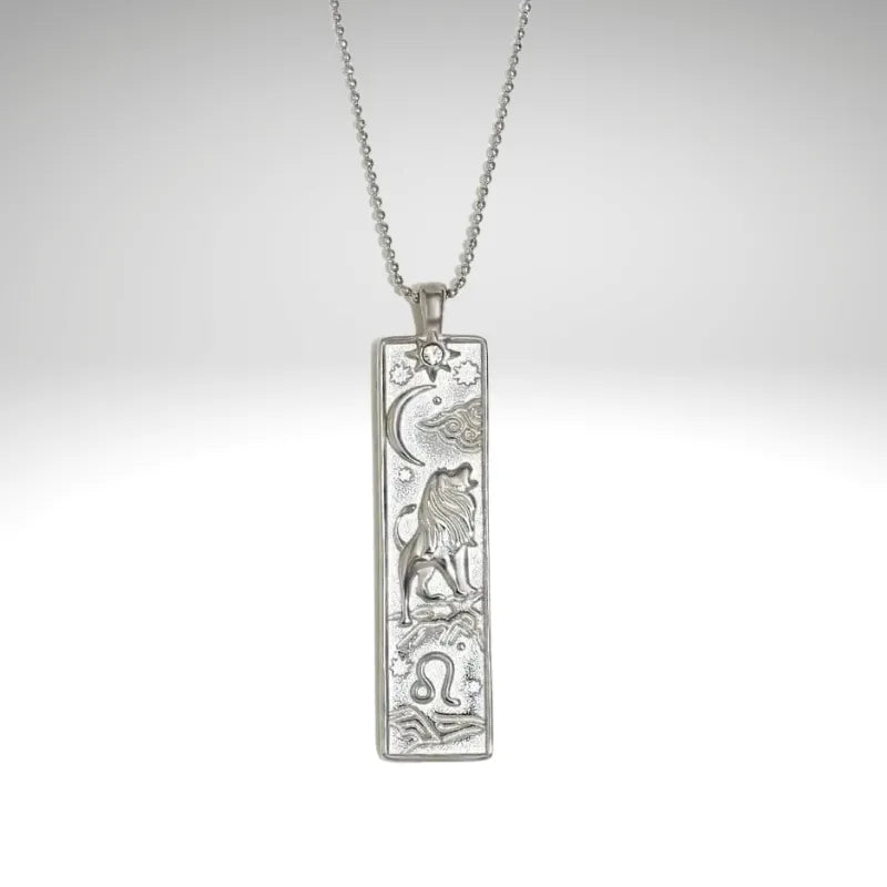 Silver pendant with zodiac design on a chain against a light gray background