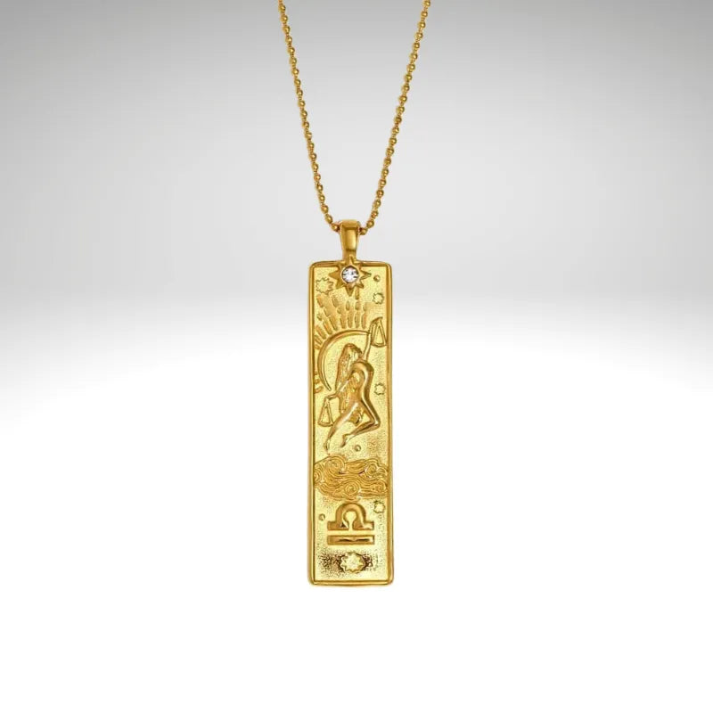 Gold pendant necklace with zodiac design on a gray background