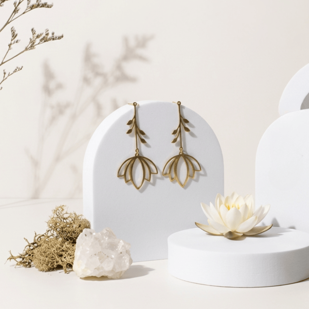 Gold leaf earrings on a white stand with decorative elements on a light background