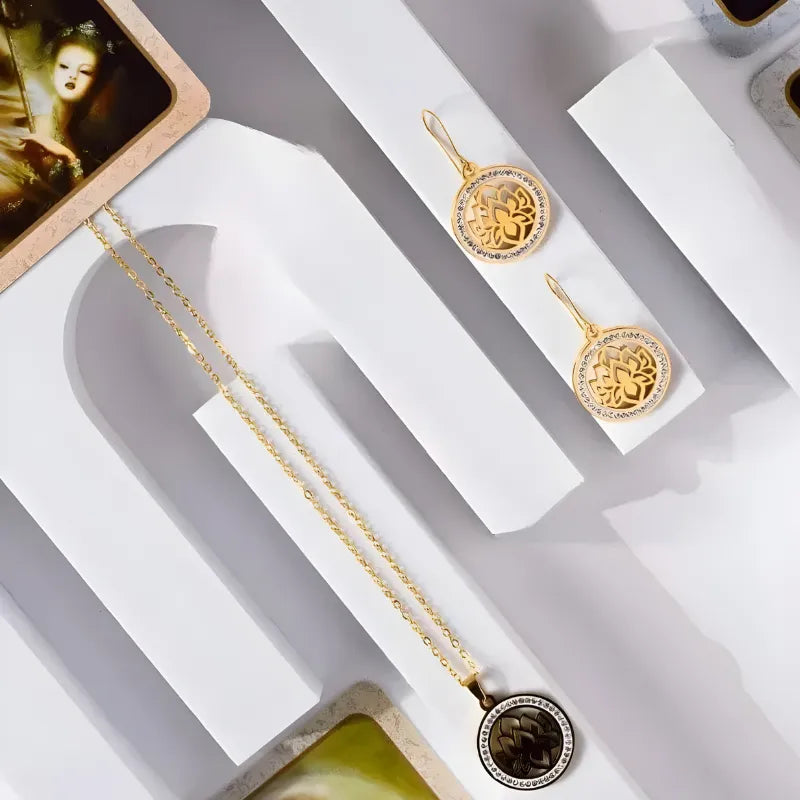 Gold jewelry set with necklace and earrings on a white display stand.