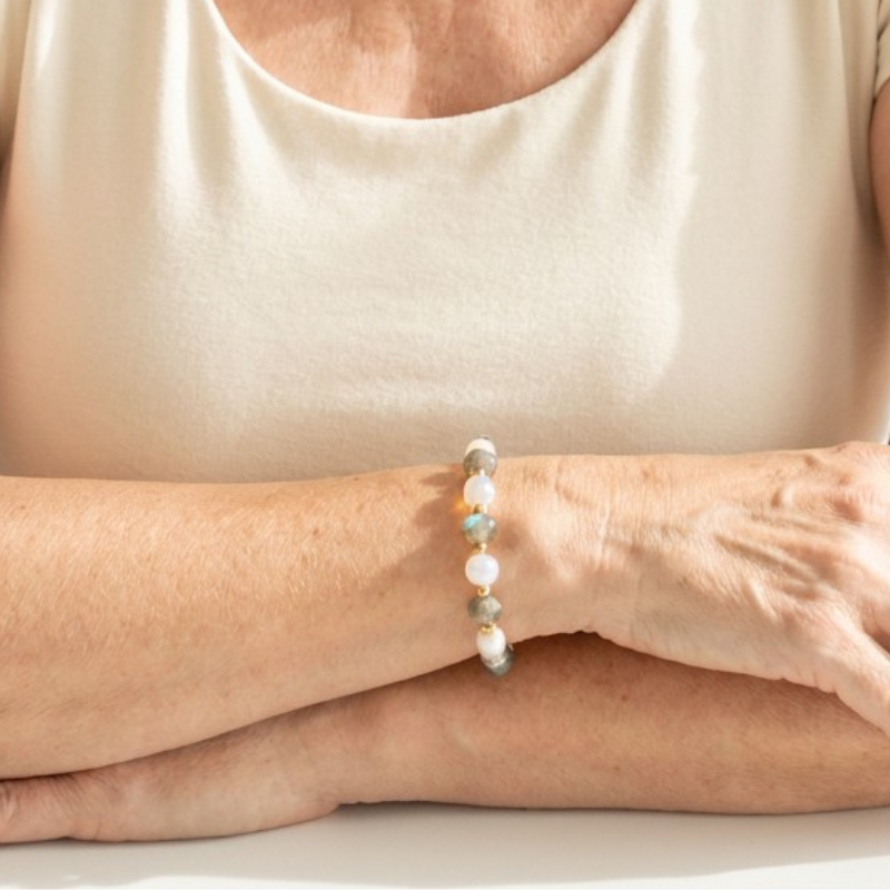 Person wearing a bracelet with small beads on a plain background
