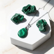 Malachite necklace and earrings on a white stand with malachite stones.