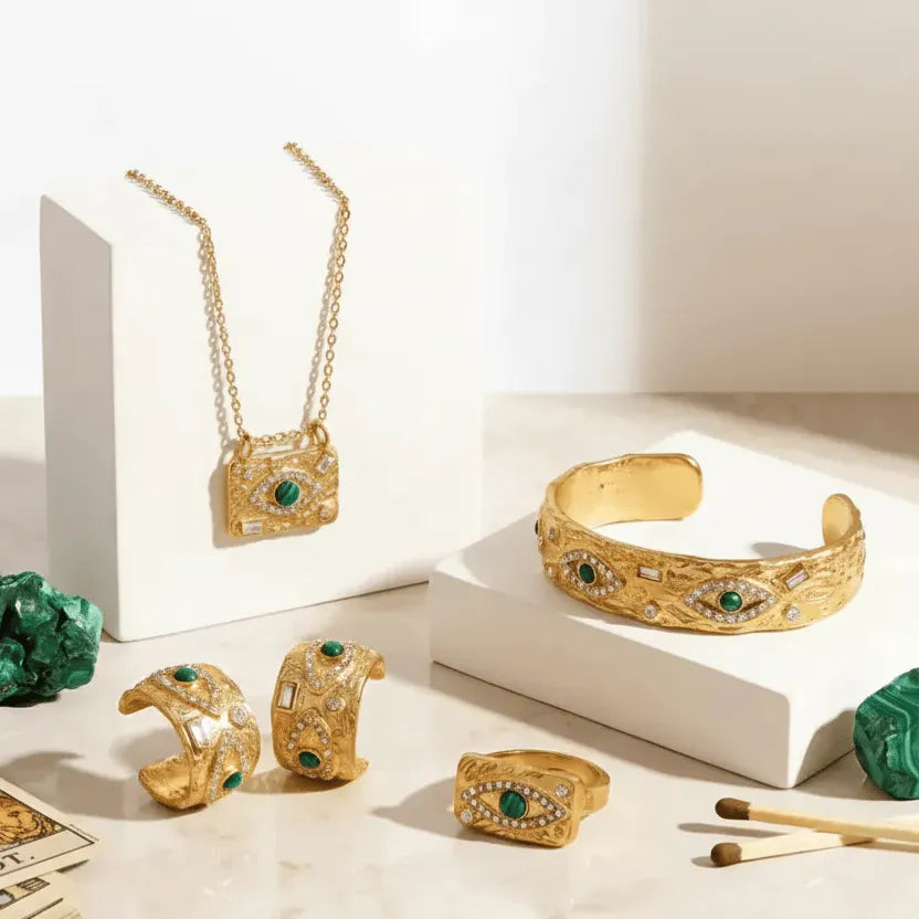 Gold jewelry set with green gemstones on a white surface
