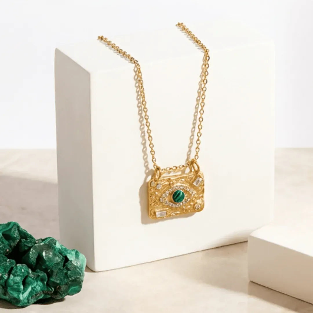 COLLECTION Gold necklace with a green gemstone pendant on a white background