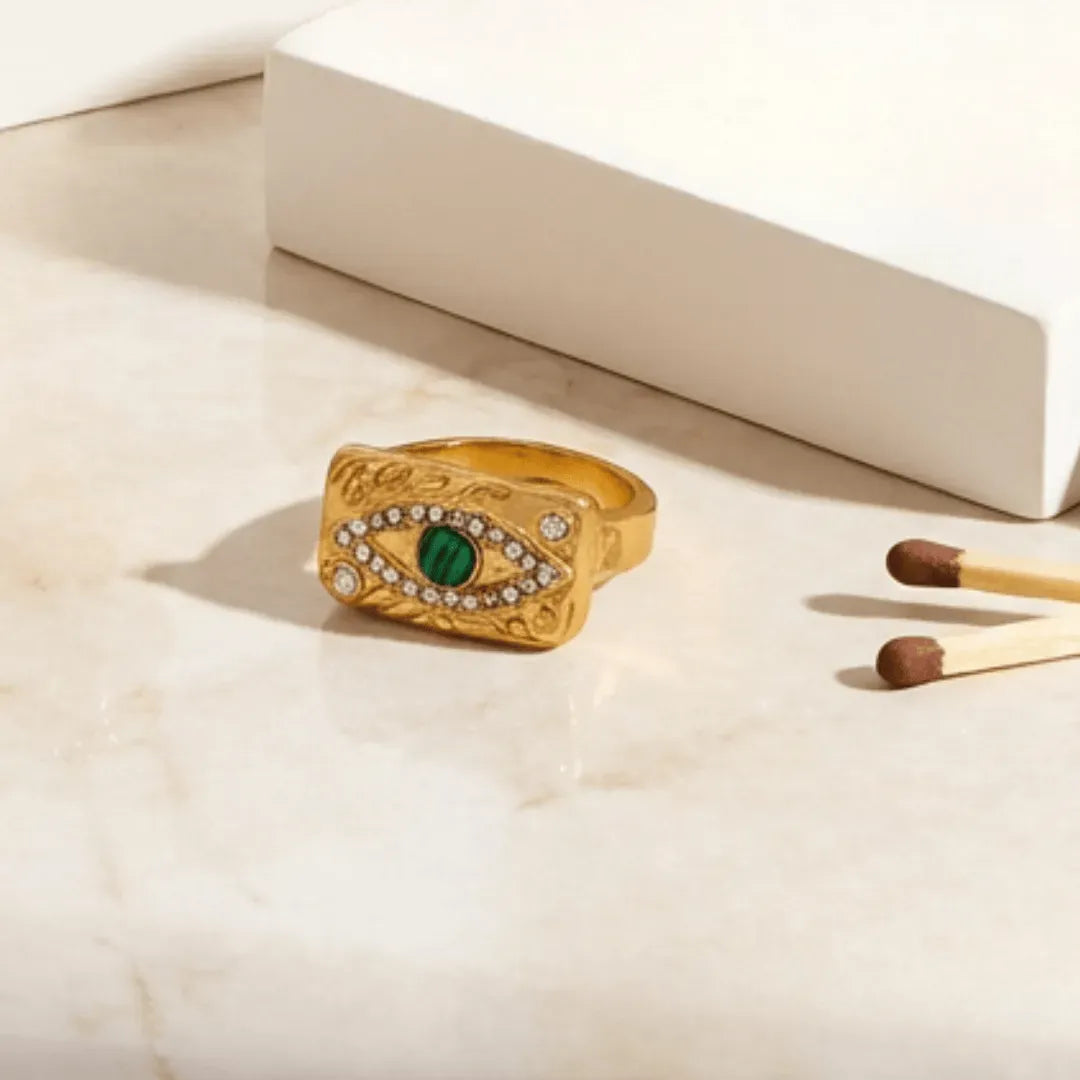 Gold ring with green gemstone on a light surface