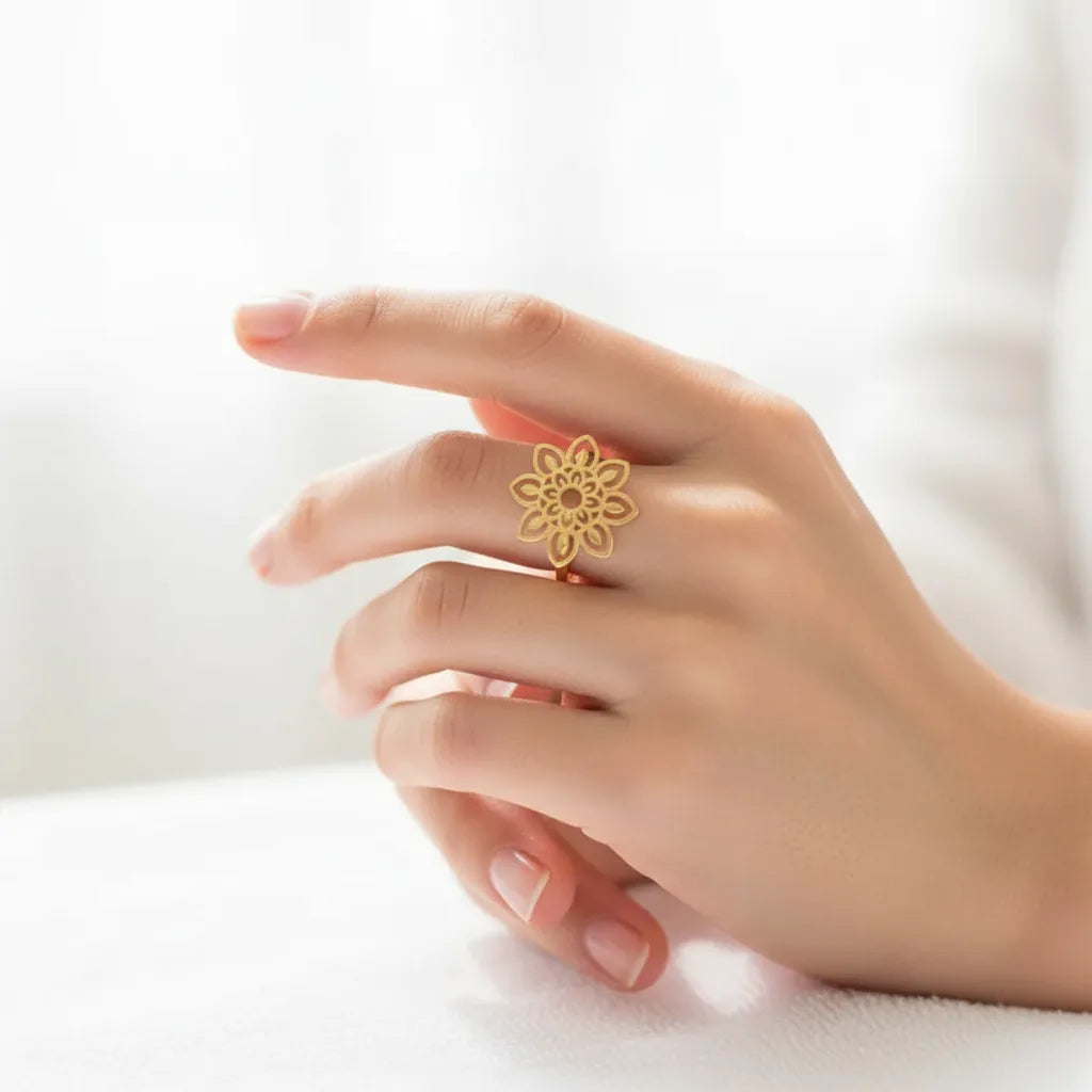 Hand wearing a gold floral ring on a white background