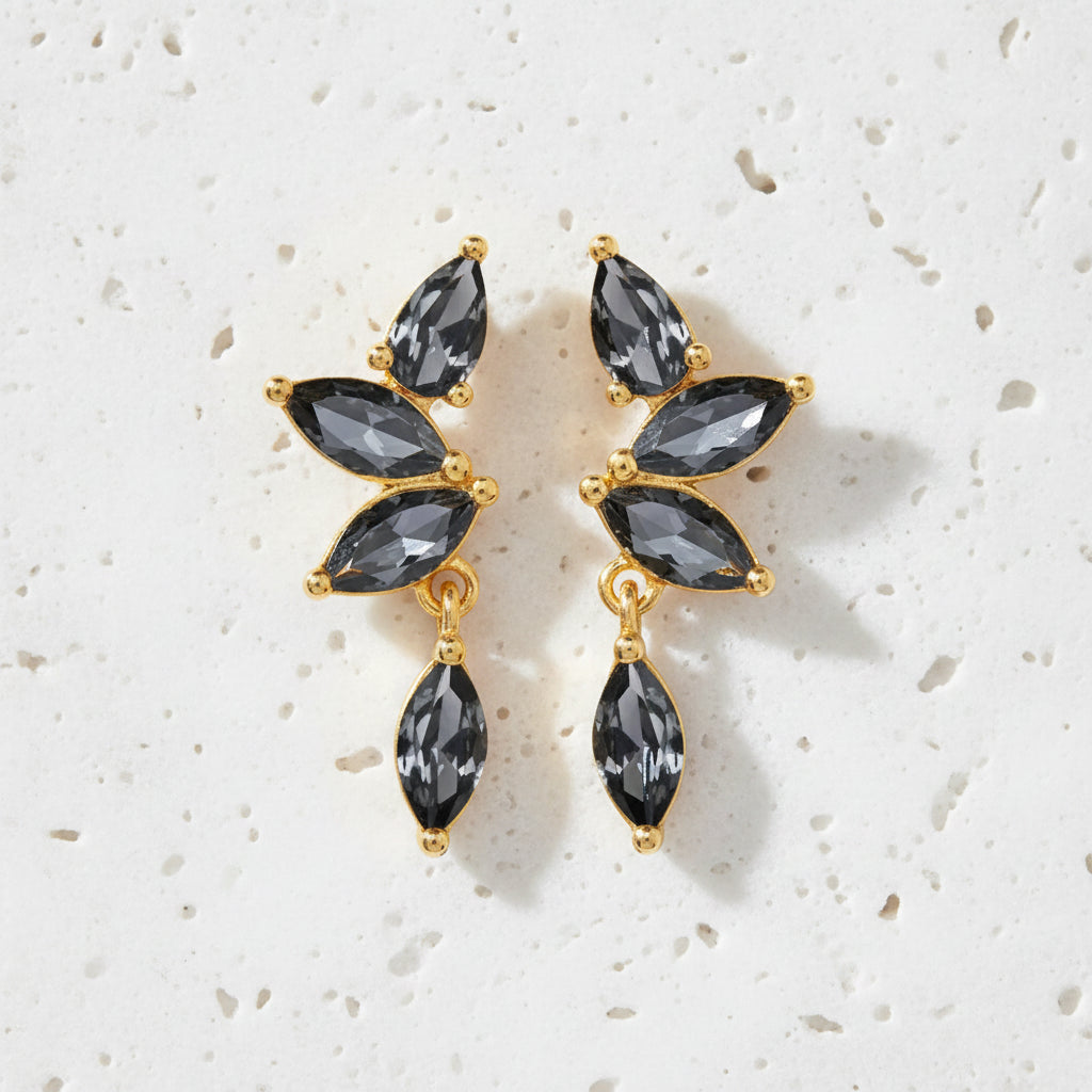 Pair of earrings with black gemstones and gold accents on a white background