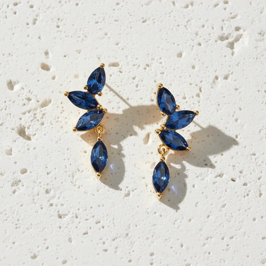 Gold earrings with blue gemstones on a white background