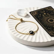 Gold bracelet with a black stone on a white dish with a tarot card in the background