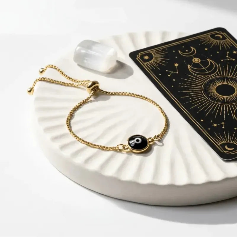 Gold bracelet with a black stone on a white dish with a tarot card in the background