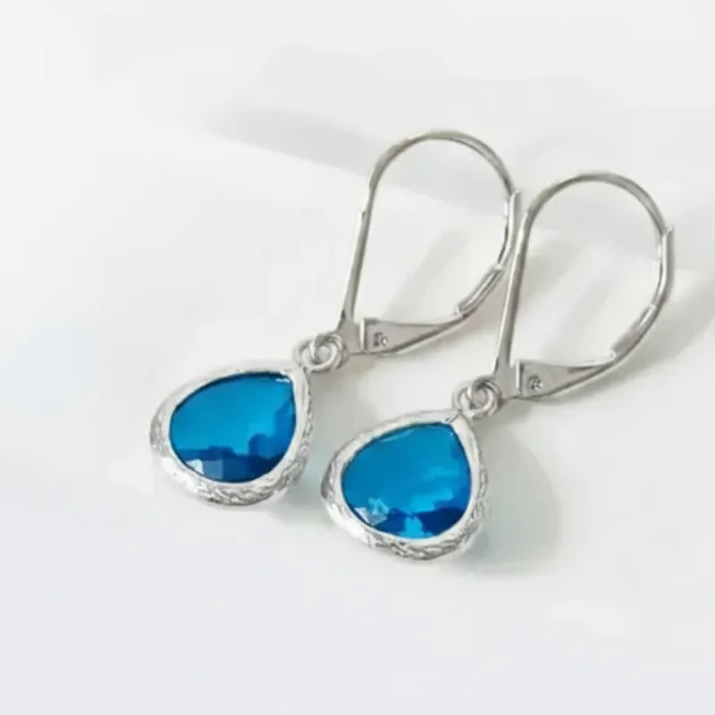Silver earrings with blue gemstones on a white background