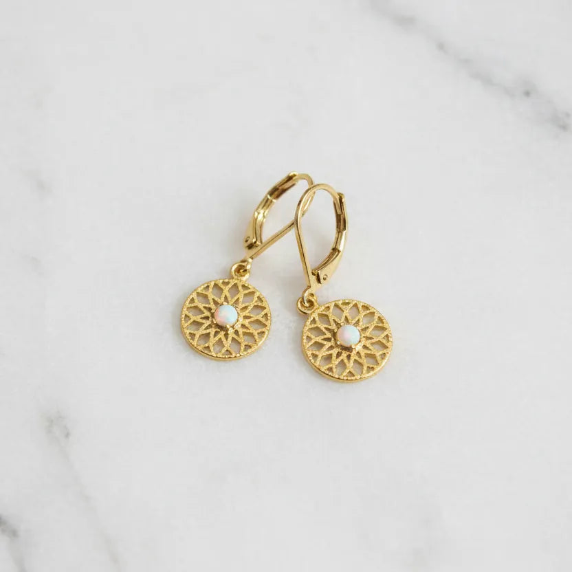 Gold filigree sun medallion drop earrings with simulated opal centre stone on leverback — celestial jewelry styled on warm fur texture