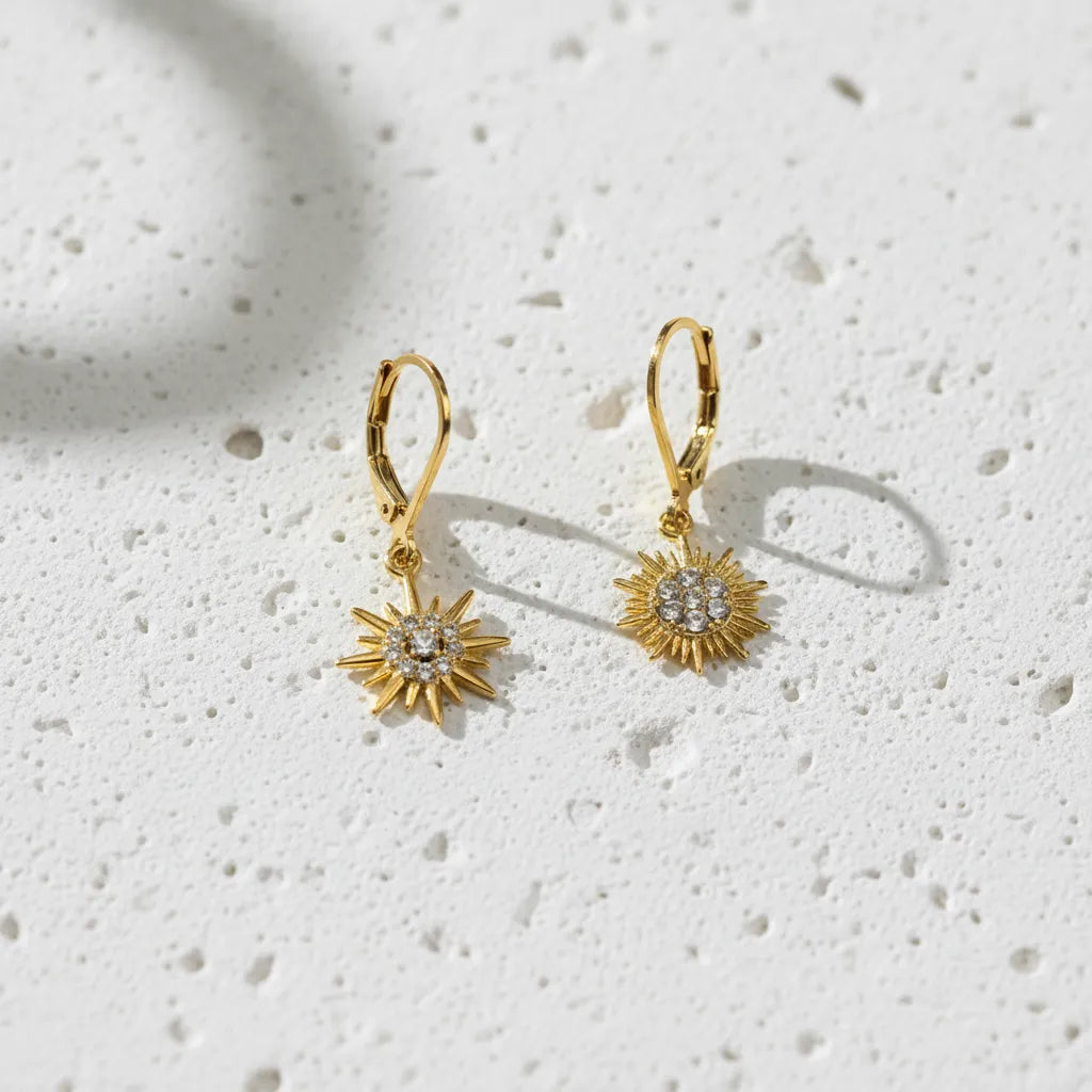 Gold sun-shaped earrings on a wooden surface