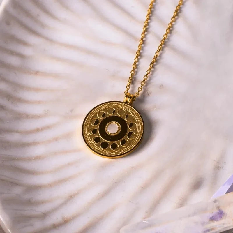 Gold necklace with a circular pendant on a shell background