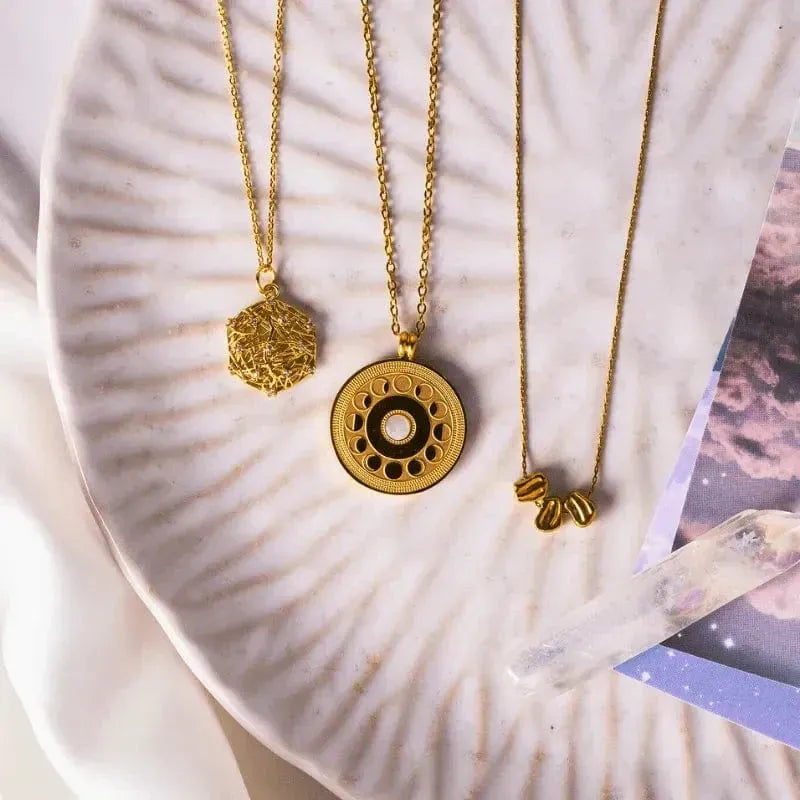 Three gold necklaces on a textured surface with a blurred background
