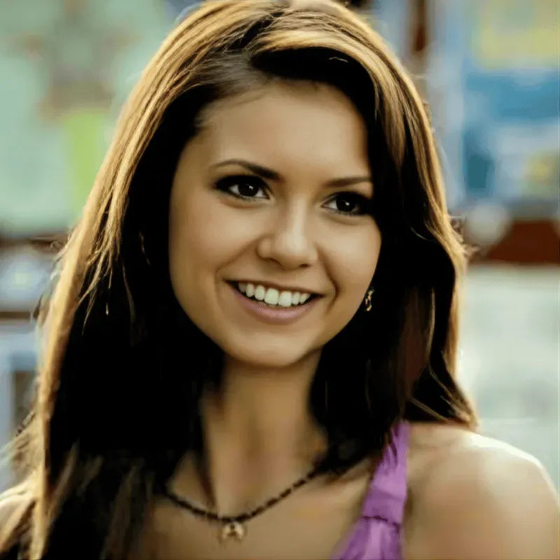 Woman with long brown hair smiling in a blurred indoor setting