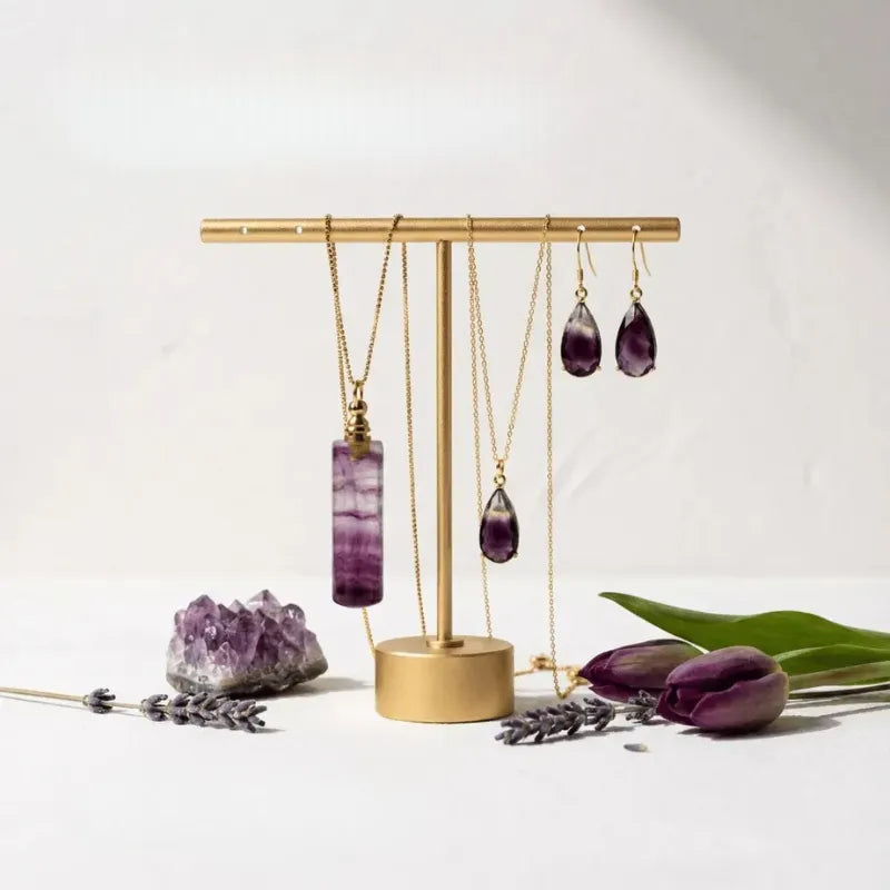 Gold jewelry stand with purple necklaces and earrings on a white background
