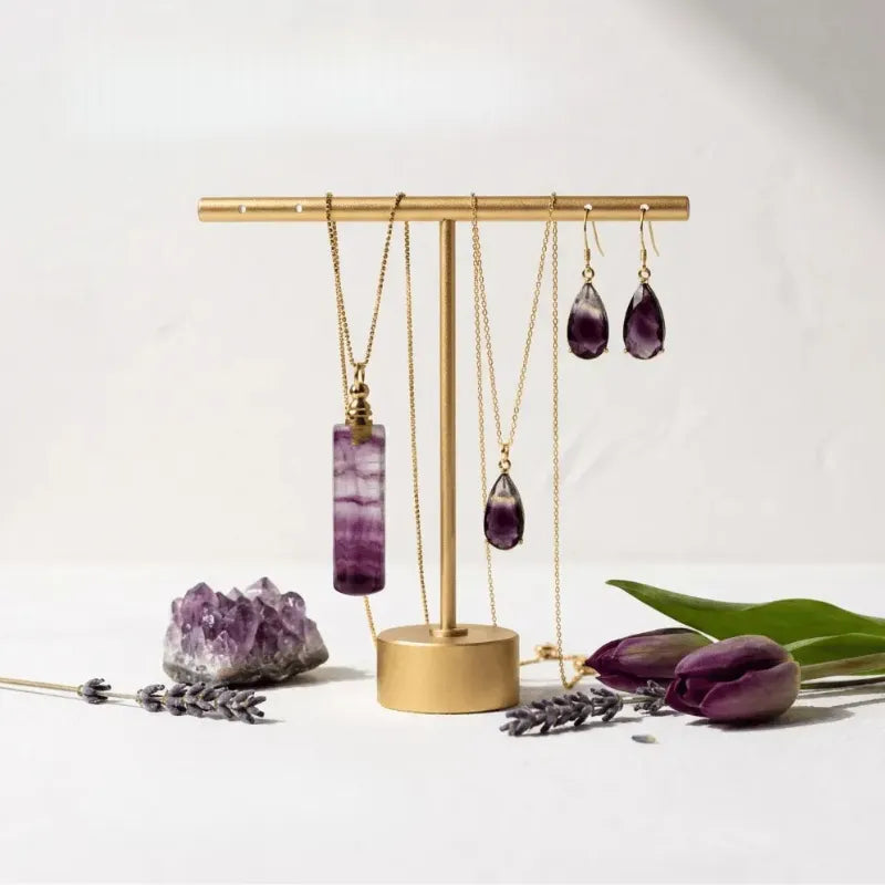 Gold jewelry stand with purple amethyst jewelry on a white background