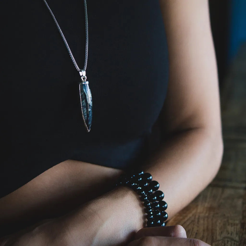 Person wearing a necklace and bracelet on a wooden surface