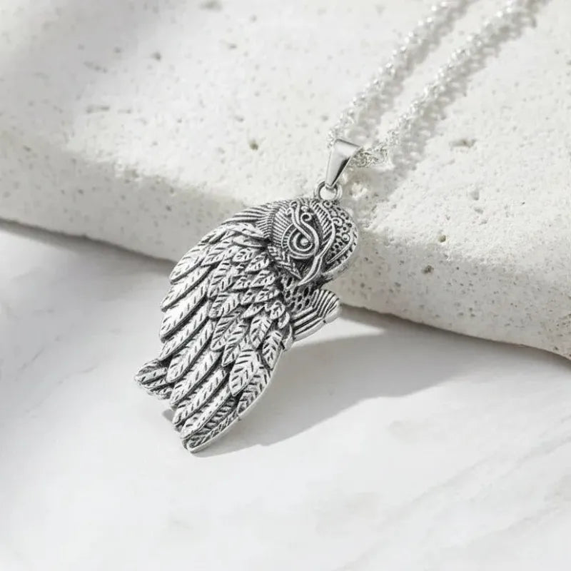 Silver winged pendant on a white stone surface