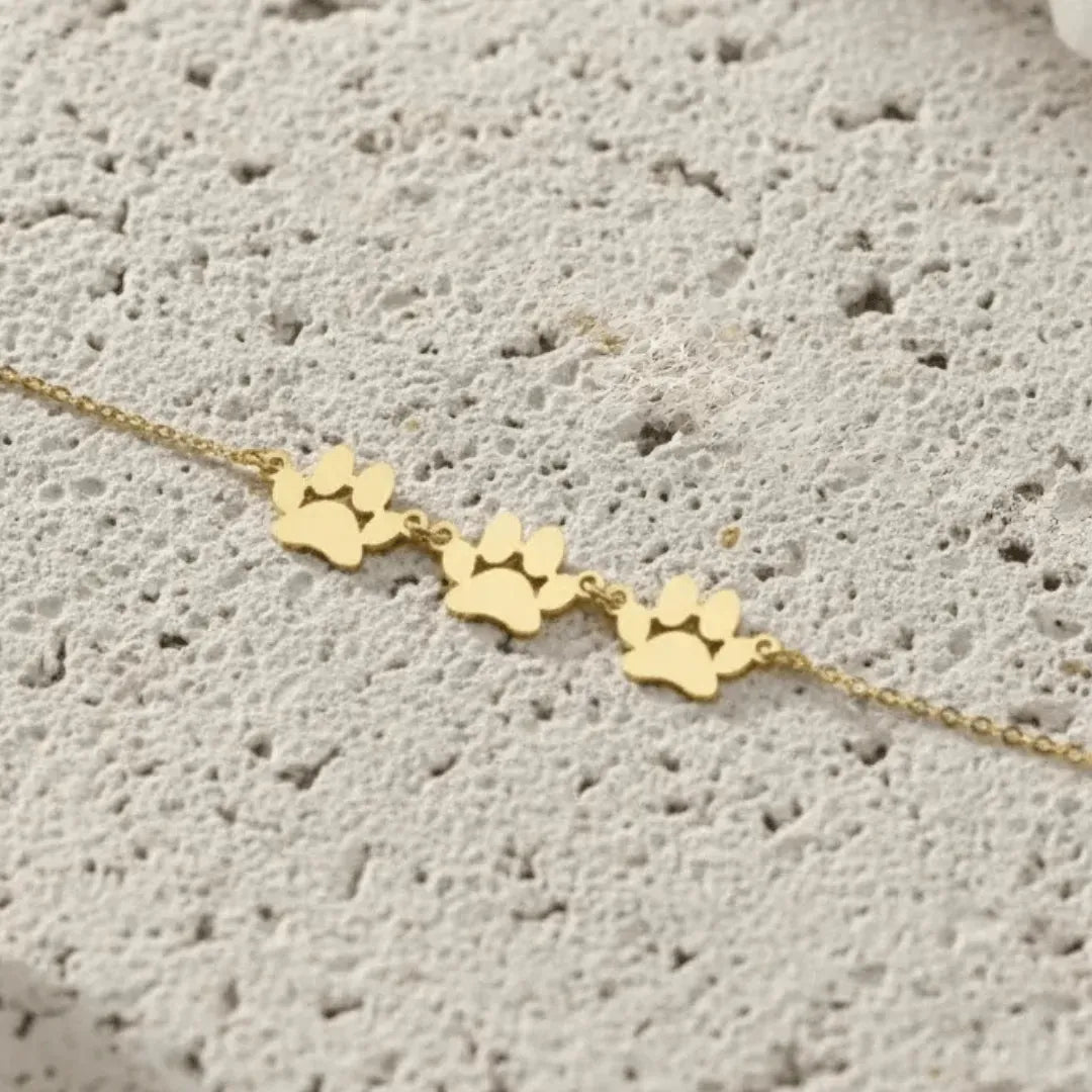 Gold paw print bracelet on a textured surface