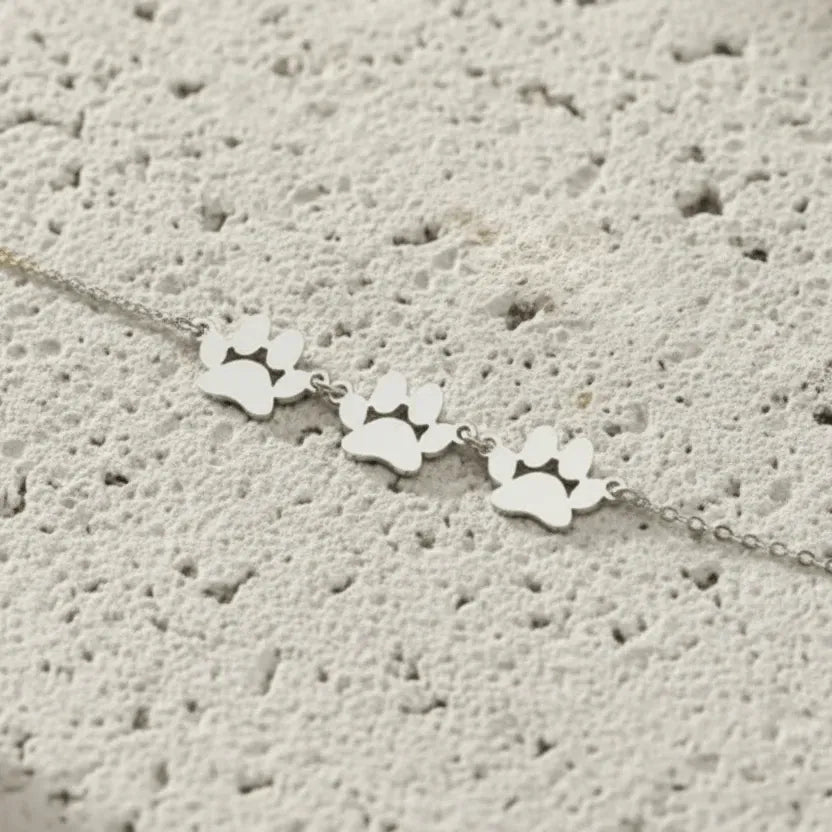 Gold paw print bracelet on a textured surface