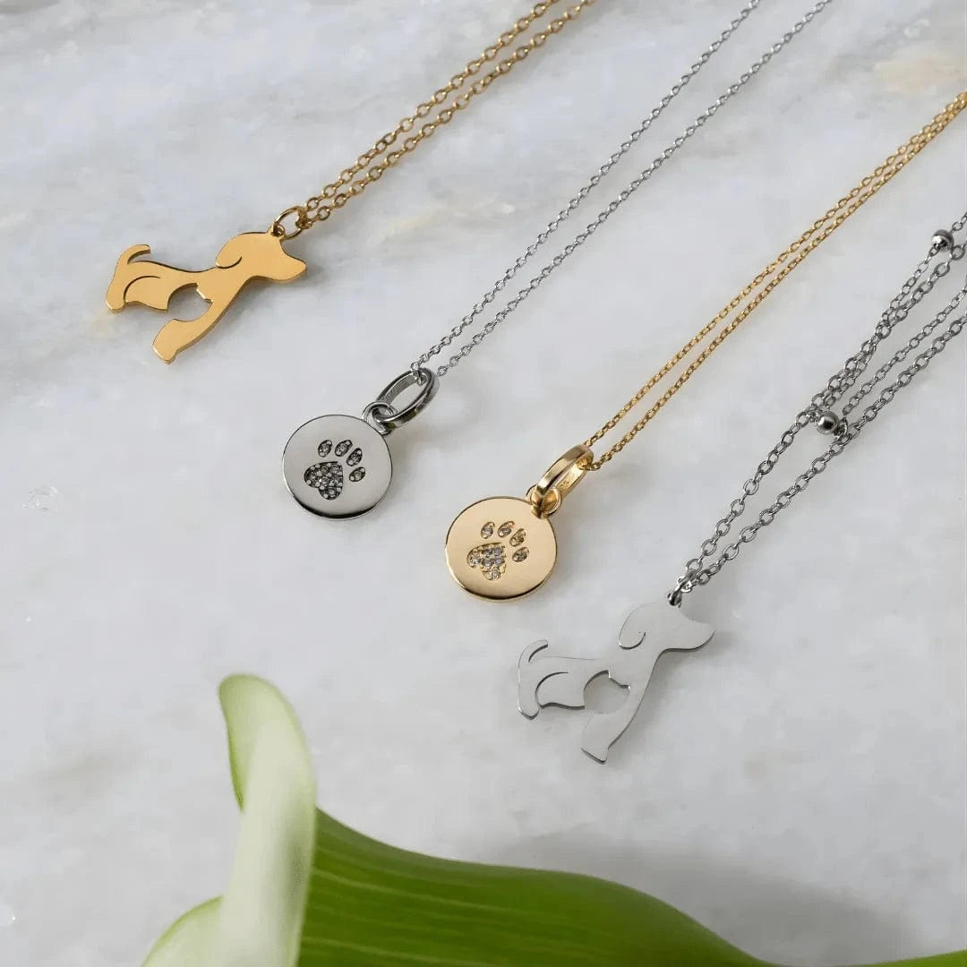Collection of dog-themed necklaces on a marble surface with a green leaf.