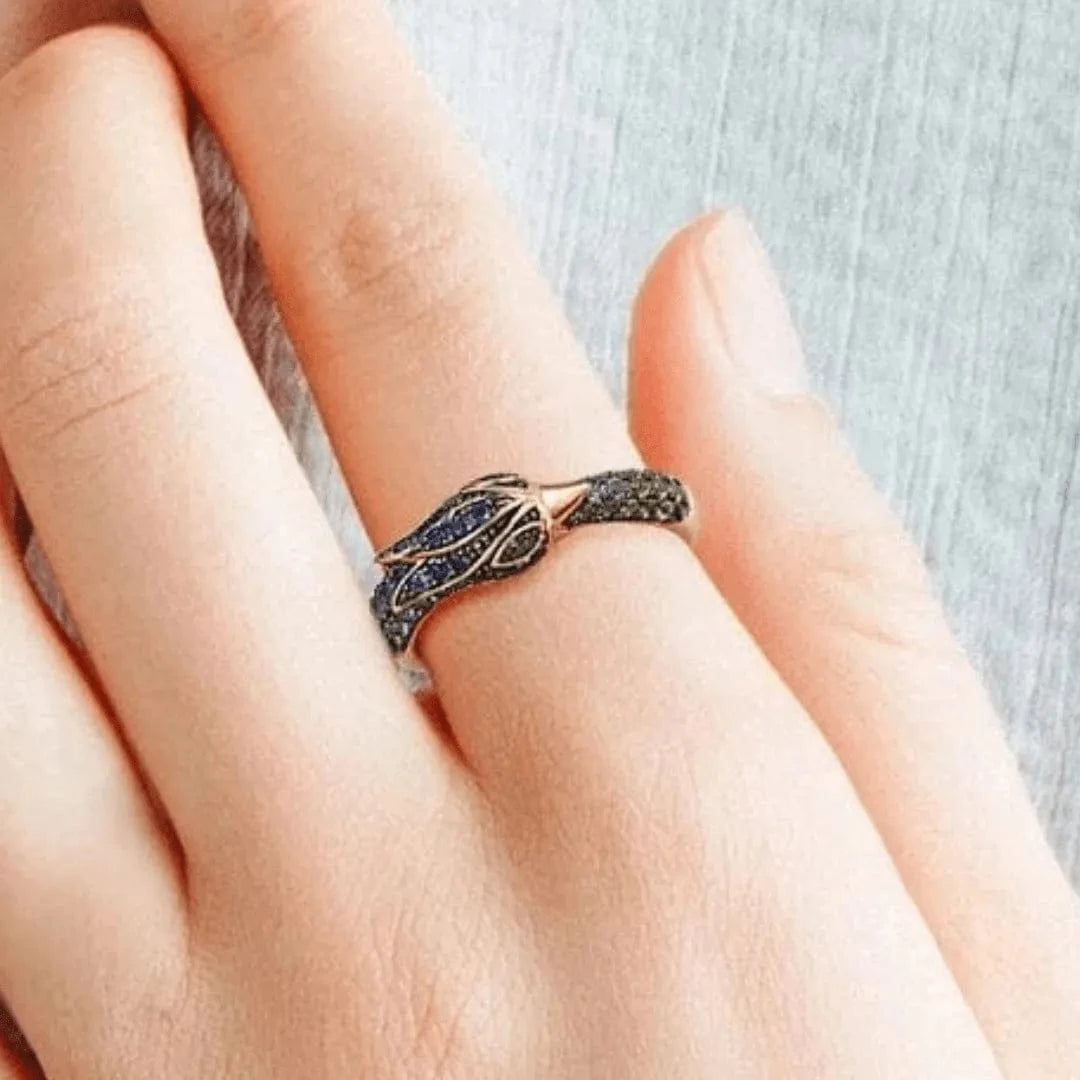 Close-up of a hand wearing a decorative ring with gemstones on a neutral background
