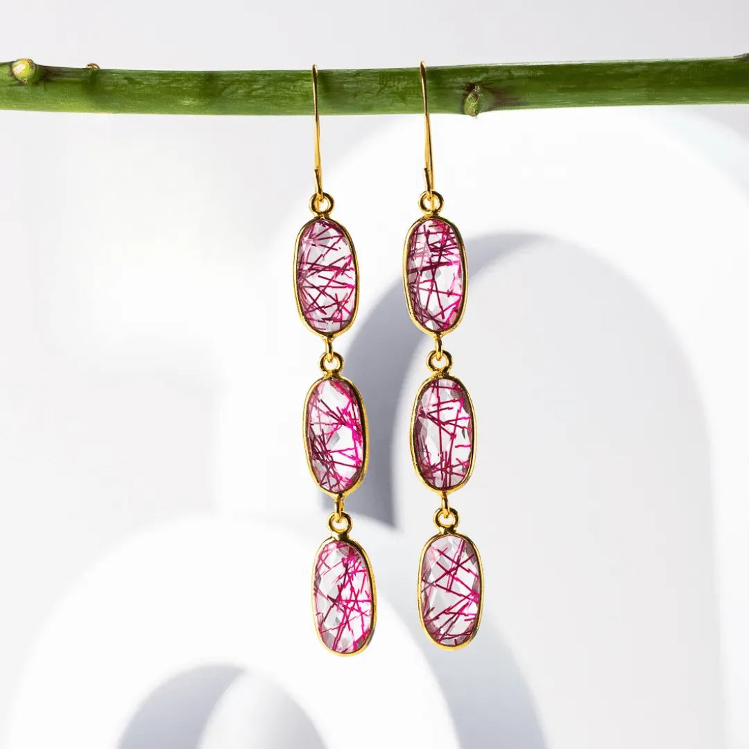 Pink gemstone earrings with gold hooks on a white background