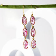 Pink gemstone earrings with gold hooks on a white background