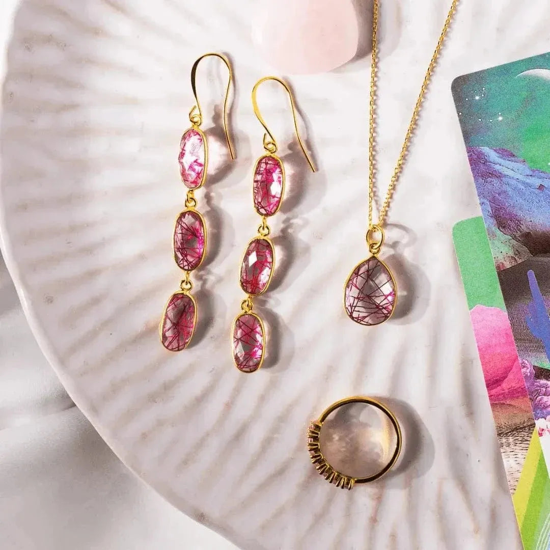 Gold jewelry set with pink gemstones on a shell