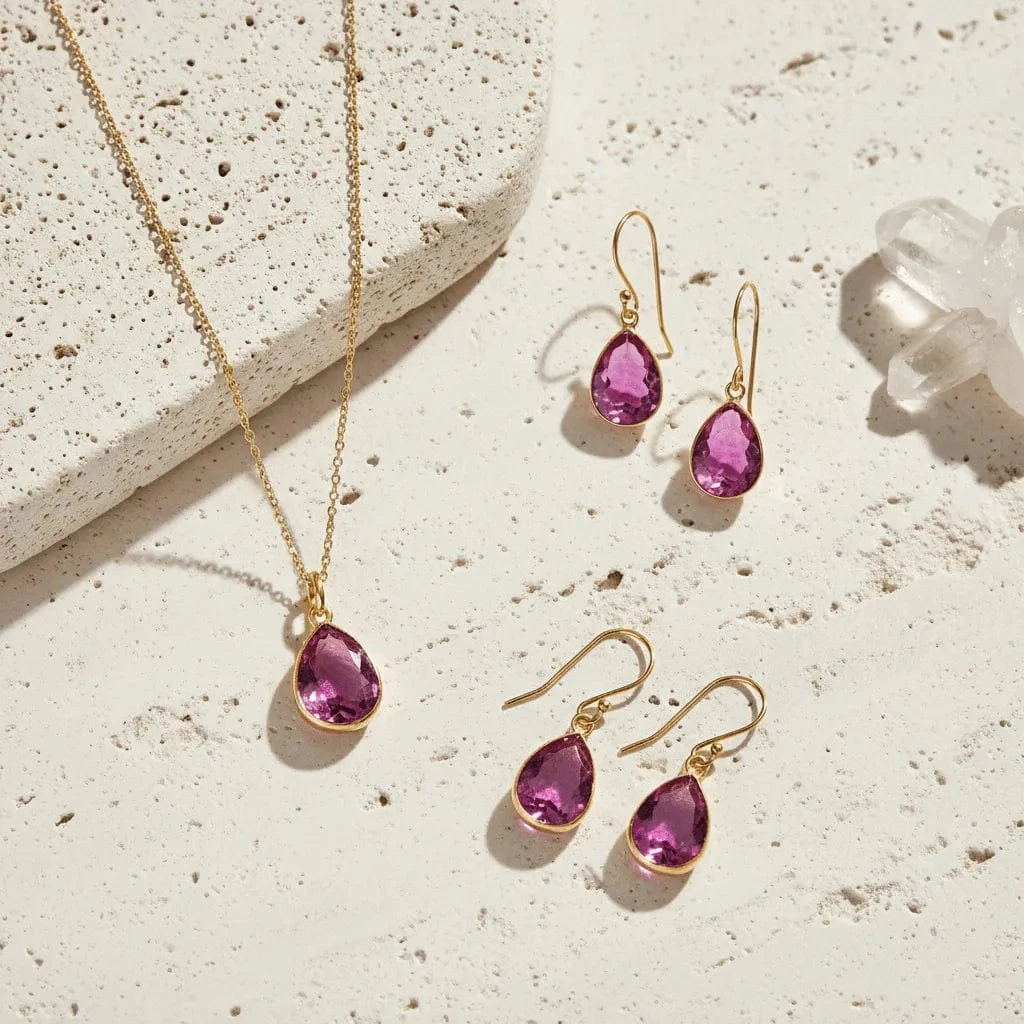 Gold jewelry set with purple gemstones on a textured surface