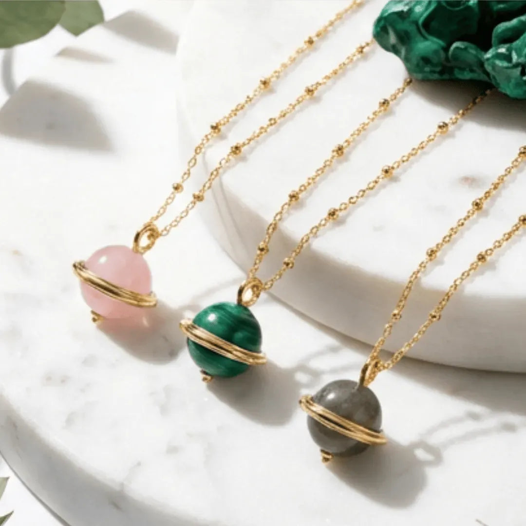 Three gold necklaces with colorful beads on a white surface