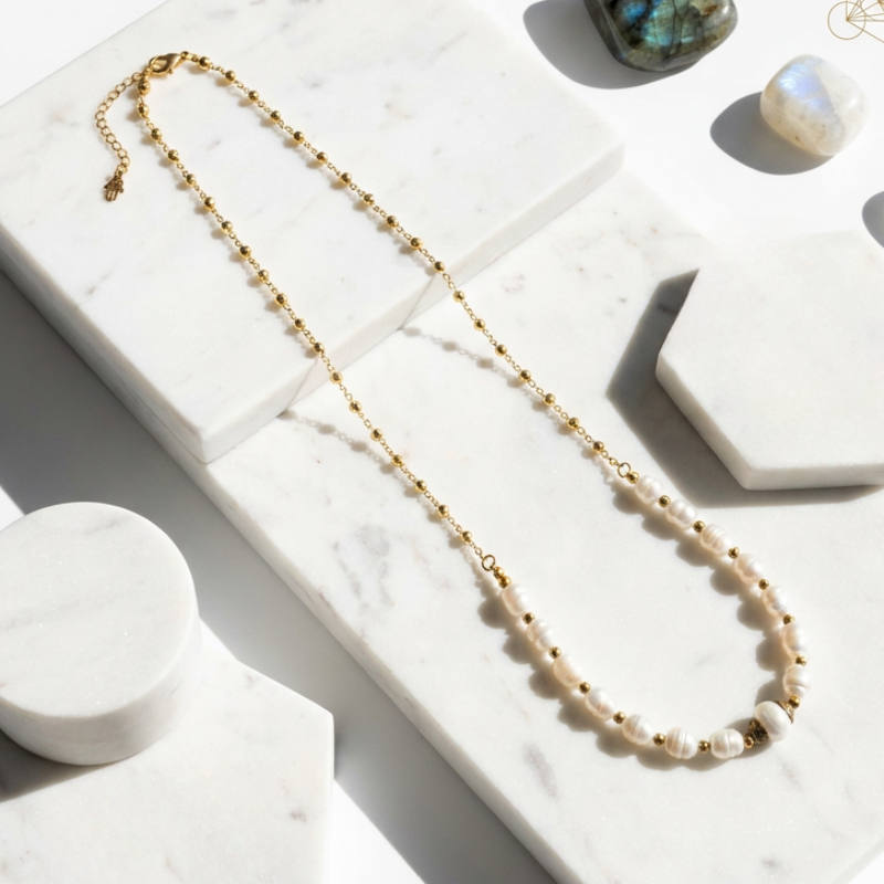 Necklace with pearls and gold chain on a marble surface