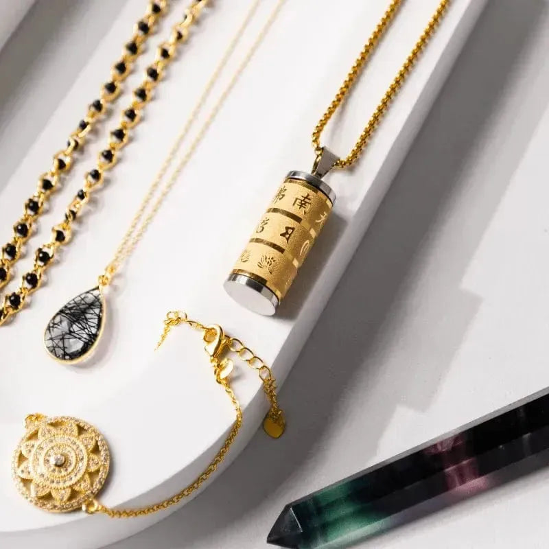 Gold necklaces and pendants on a white surface with a crystal