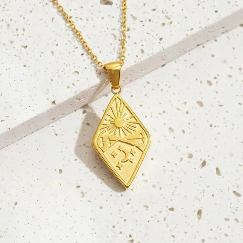 Gold necklace with a diamond-shaped pendant on a textured white surface