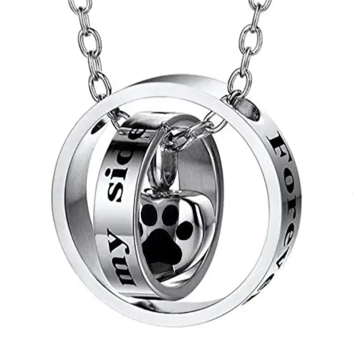 Heart urn necklace featuring a spinning design with engraved paw print and words 'Forever by my side'.