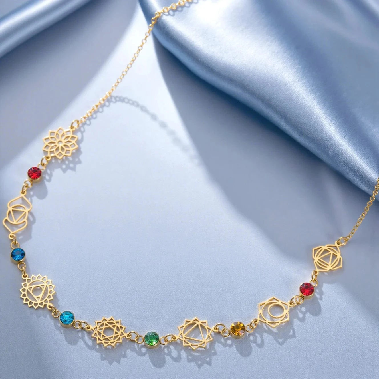 Gold necklace with colorful beads on a light blue fabric background