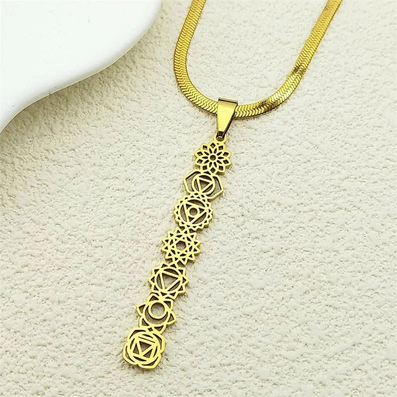 Gold necklace with a detailed pendant on a textured beige surface