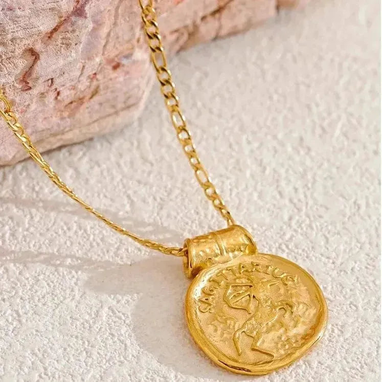 Gold necklace with a coin pendant on a textured surface