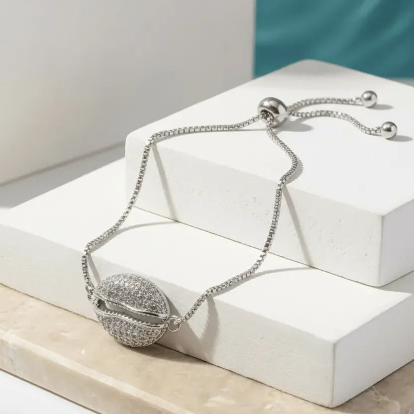 Silver bracelet with a round, ball-like clasp on a white surface
