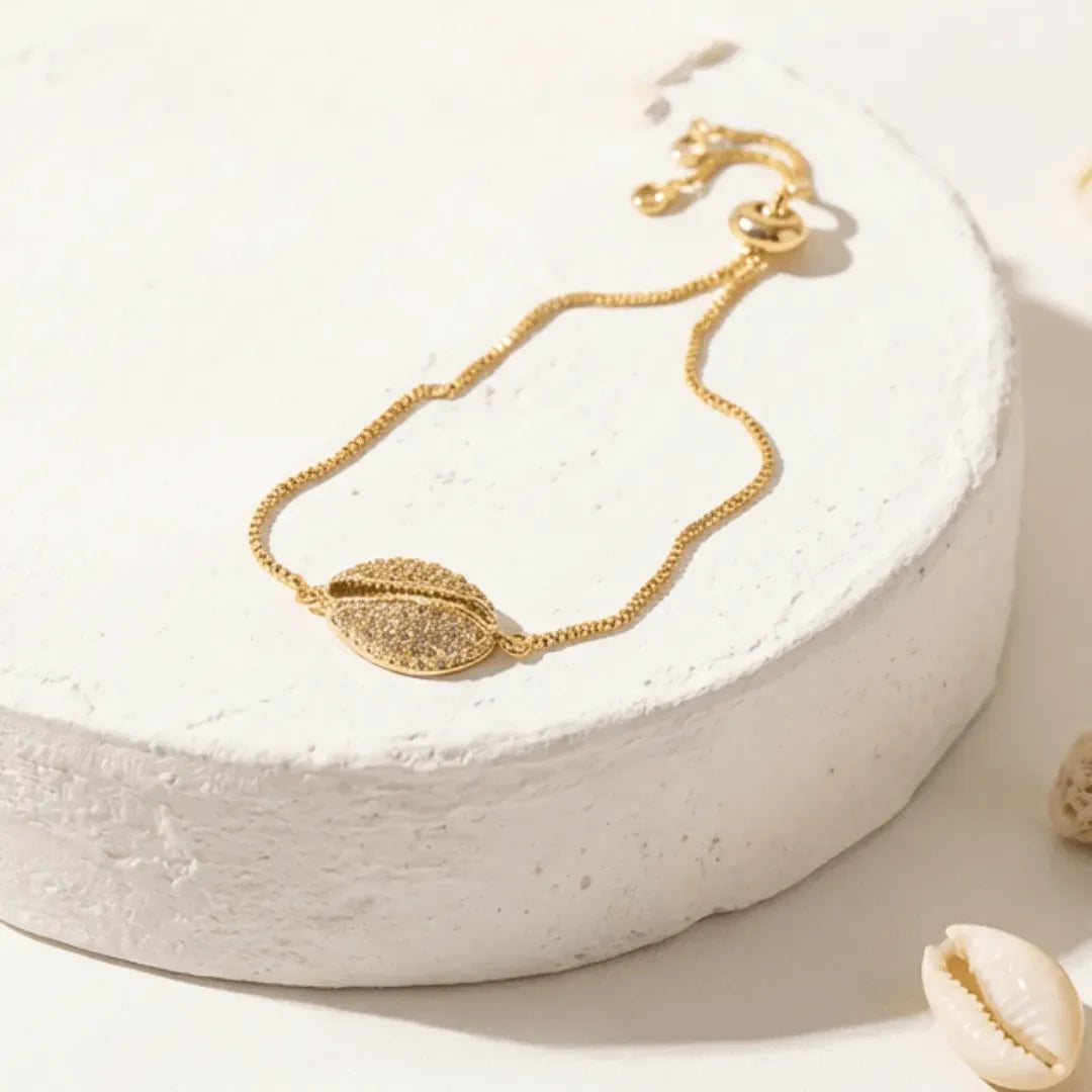 Gold bracelet with leaf design on a white stone surface