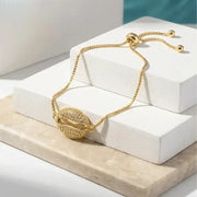 Gold bracelet on a white box with a marble surface