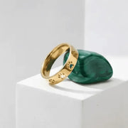 Gold ring with paw print design on a green stone block against a white background