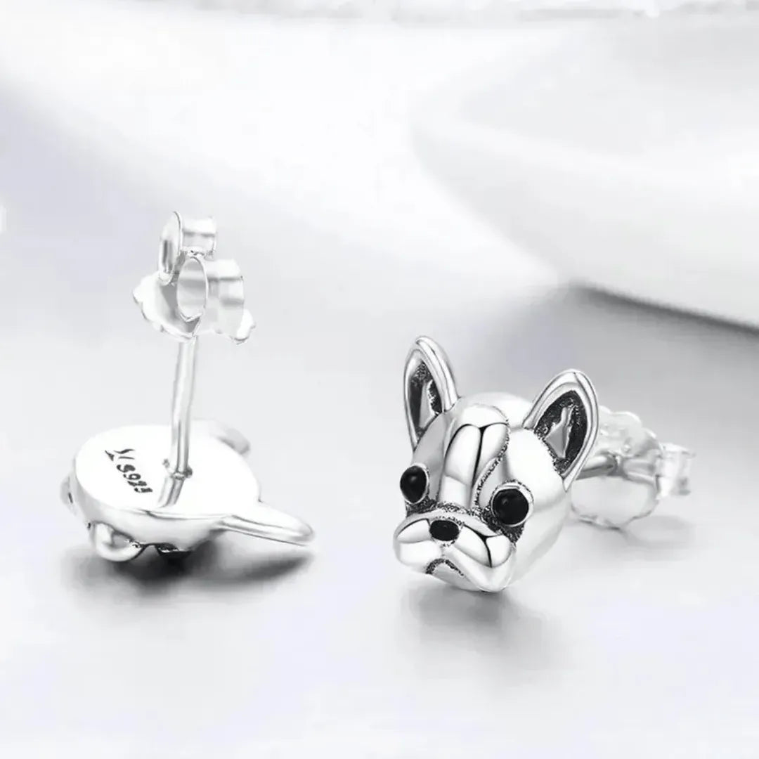 Silver dog-shaped earrings on a white background