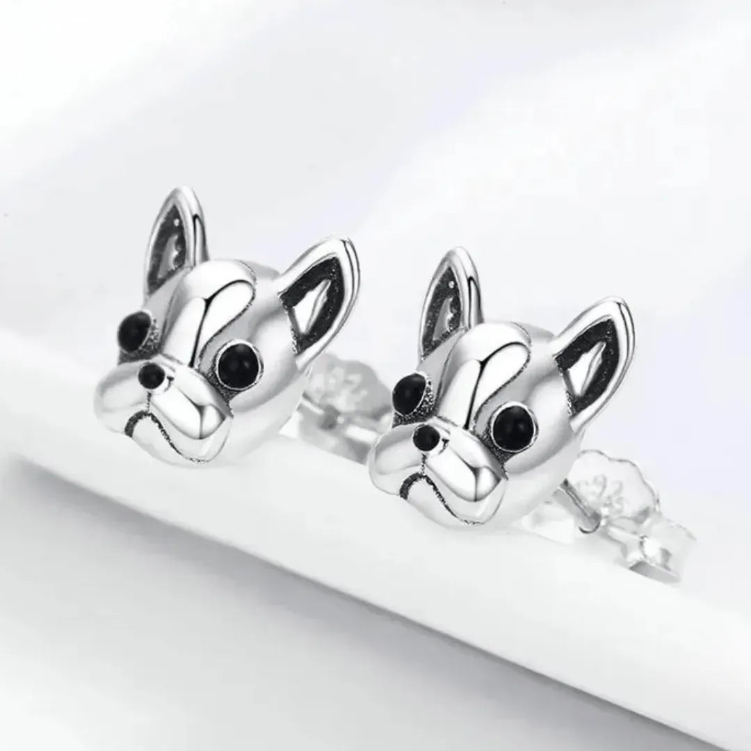 Silver dog-shaped earrings on a white background