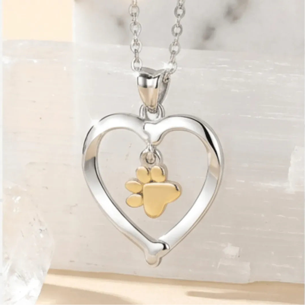Heart-shaped silver pendant with a gold paw print on a light background