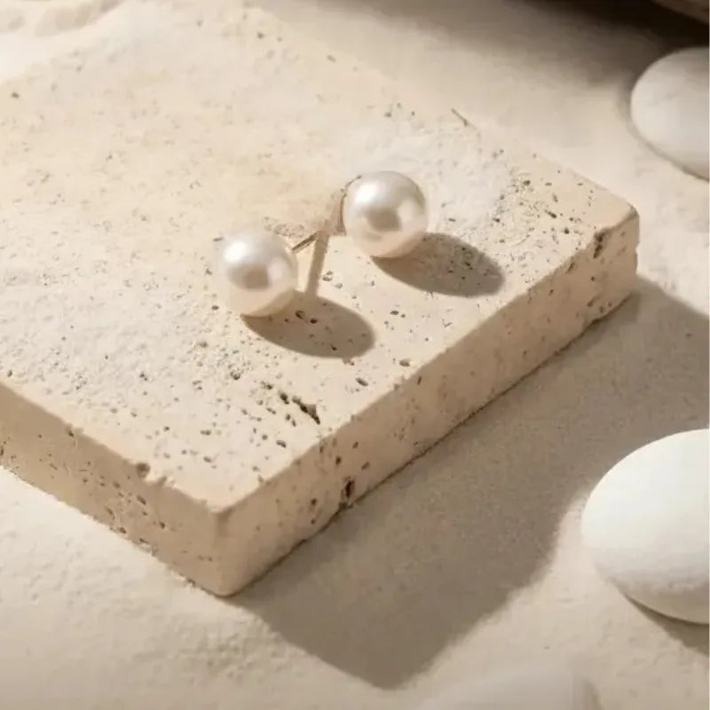 Pearl earrings on a textured beige surface
